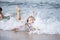 Girl in a turquoise bathing suit in the sea, happy children swimming in the sea, waves and splashes from swimming in the sea