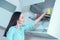 Girl in a turquoise shirt puts a yellow Cup on the drying shelf of the kitchen cupboard