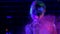 Girl in ultraviolet light blows pink fluorescent powder with palm
