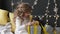 Girl unfolds a Christmas gift against the background of a garland