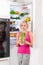 Girl unhappy look to green cabbage, refrigerator