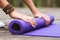 Girl unwinding gymnastic mat for yoga class outdoors