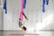 Girl in upside down inversion pose on pink silk hammock