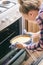 Girl using dishcloth for taking cheesecake out of oven