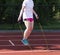 Girl using jump rope in shade on track