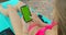 Girl using mobile phone green screen near the swimming pool. Hands holding smartphone chrome key, fingers tapping modern