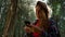 Girl using smartphone in forest. Hiker trying to find mobile network in woods