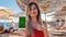 Girl on vacation show the green screen smartphone outdoor. Close up woman hand holding and using mobile smart phone with