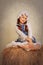 Girl in vintage style rustic sitting on a haystack.