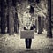 Girl with vintage suitcase and camera standing in forest and loo