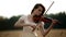 Girl violinist playing the violin in wheat field.