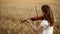 Girl violinist playing the violin in wheat field.