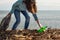 Girl volunteer helps clean the beach of debris. Earth day and environmental improvement concept