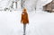 Girl walk backs winter, white village snow cold outside countryside blizzard snowfall, yellow hat travel