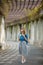 Girl walking on alley with arches and columns