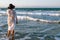 girl walking along the beach. Girl in white long summer dress on vacation. Girl on the shore of the ocean