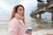 girl walking along the seashore. brunette drinks coffee. girl in a pink coat