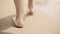 Girl walking barefoot on the beach sand along the sea. Slow motion