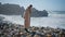 Girl walking beach stones in sunlight. Thoughtful traveler balancing rocky beach