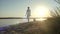 Girl walking her dog on leash at beach, against the sunset, slow motion