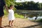 Girl walking in park in mother hand near lake river with geese duck in water