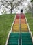 Girl walking up on the colorful stairs in the parks - outdoor woman fitness activity - metaphor of hope in the future concept -