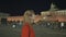 The girl walks and admires the night red square and the Kremlin in Moscow.