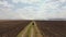 A girl walks along the road in the field to the place where there is a fire