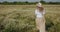 The girl walks away through the chamomile field