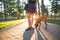 Girl walks the dog by leash in the park on the background of the sun. Walk with a puppy in the open air