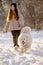 A girl walks with her beloved pet Samoyed in winter on the shore of a lake in the park.