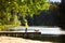 A girl walks her dog in the Park. A child and a red Dachshund on a leash stands on a bridge near the water in autumn in Sunny