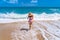 A girl walks on the ocean foam on a sandy beach. Beautiful girl on the background of the ocean on the Paradise beach of