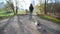 Girl walks with pet along fall park against city buildings