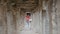 Girl walks through the ruins between the columns of an ancient architectural structure, Hampi