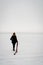 Girl walks on a snow-covered lake. Sad mood in black clothes.