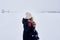 Girl walks through a snowstorm and looks at an old abandoned water intake on a frozen river