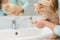 A girl washes a cats paw under a stream of water from a washbasin mixer in the bathroom