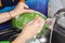 A girl washes a green pot at home in the kitchen with dish detergent