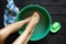 girl washes her feet in a bowl of water on the wooden floor at home, foot care, wash feet at home