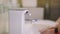 The girl washes her hands using an automatic soap dispenser in the bathroom.