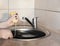The girl washes a large dirty frying pan with a sponge and soap under running water under the tap
