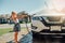 Girl washing car on driveway in front house on sunny summer day