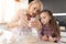 The girl watches as her grandmother drives the egg into the dough for a homemade pie