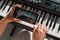 A girl watches an online music lesson on a smartphone and learns to play the piano. Close-up of woman`s hands on keys.