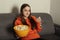 Girl watches TV and eats pop corn, smiles