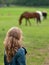 Girl watching horses in field