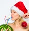 Girl wear santa hat hold ornament ball drink watermelon cocktail straw white background. Winter detox concept. Woman