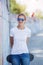 Girl wearing blank white t-shirt, jeans posing against rough street wall