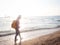 Girl wearing Blue jeans and red plaid shirt and backpacking yellow doing walking on the sea